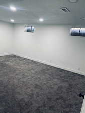 Basement with dark colored carpet, a textured ceiling, and recessed lighting