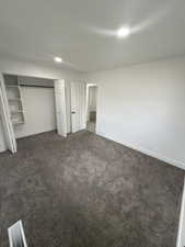 Unfurnished bedroom featuring a closet, dark carpet, and recessed lighting