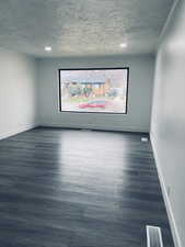 Unfurnished room with dark wood-style flooring, recessed lighting, and a textured ceiling