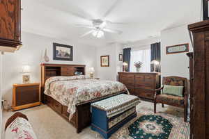 Carpeted bedroom with a ceiling fan