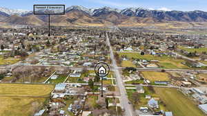 Aerial view of property and surrounding area featuring nearby suburban area and a mountainous background