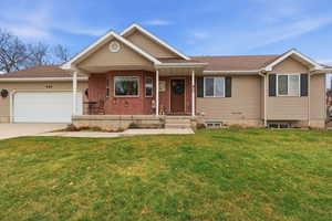 Single story home featuring a shingled roof, covered porch, driveway, and a front lawn