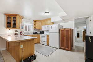 Kitchen featuring light countertops, white appliances, light flooring, a peninsula, and open shelves