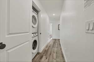 Laundry room featuring estacked washer and dryer, light wood-type flooring, and recessed lighting