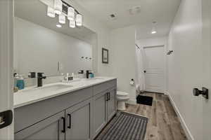 Full bath featuring double vanity, light wood finished floors, recessed lighting, and shower / bath combo with shower curtain