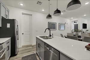 Kitchen featuring gray cabinetry, hanging light fixtures, appliances with stainless steel finishes, recessed lighting, and open floor plan