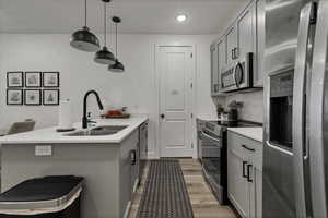 Kitchen with gray cabinetry, stainless steel appliances, a peninsula, hanging light fixtures, and recessed lighting