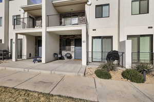 Rear view of house featuring stucco siding, a balcony, and stone siding