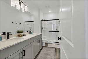 Full bathroom featuring a stall shower, double vanity, and dark wood-style flooring