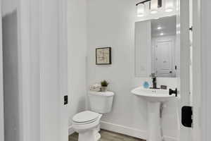 Half bath with toilet and light wood-style flooring
