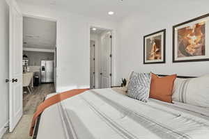 Bedroom with stainless steel fridge, recessed lighting, and light wood-style floors