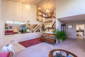 Foyer with stairway, a high ceiling, tile patterned flooring, a chandelier, and carpet floors