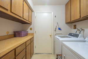 Laundry room with cabinet space, washer and dryer, and light floors