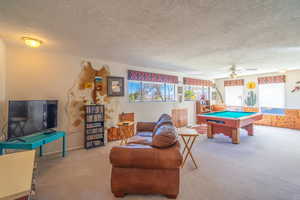 Primary Bedroom used as game room with a textured ceiling, pool table, carpet, and ceiling fan