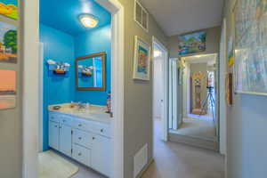 Bathroom with vanity, light carpet, and a textured ceiling