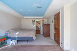 2nd Bedroom with light carpet and a tray ceiling