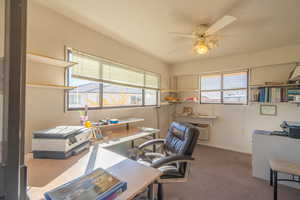 Office area with dark colored carpet and a ceiling fan