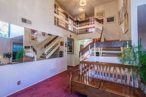 Stairs featuring a towering ceiling and carpet