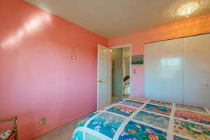 Carpeted 4th bedroom featuring a textured ceiling and a closet