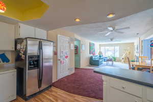 Kitchen with white cabinetry, stainless steel refrigerator with ice dispenser, a textured ceiling, light carpet, and open floor plan