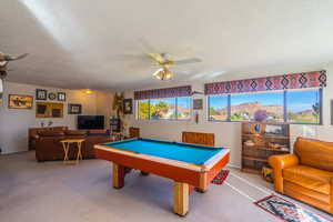 Primary bedroom used as game room with pool table, a textured ceiling, carpet flooring, and a ceiling fan