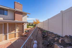 View of side of home with brick siding, a chimney, a sunroom, and stucco siding