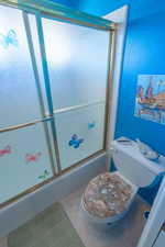 Full bath featuring enclosed tub / shower combo and toilet