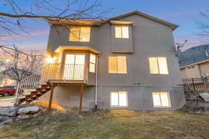 Back of house with a lawn, stairs, and stucco siding