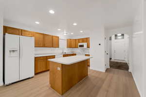 Kitchen with white appliances, light countertops, arched walkways, recessed lighting, and a center island