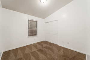 Spare room featuring vaulted ceiling and carpet floors