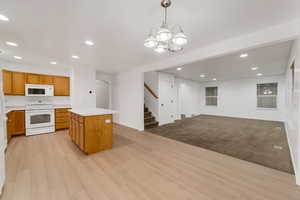 Kitchen featuring recessed lighting, light countertops, white appliances, hanging light fixtures, and arched walkways