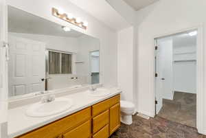Bathroom featuring double vanity, a spacious closet, stone finish flooring, and a bath