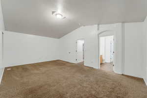 Unfurnished room with vaulted ceiling and carpet flooring