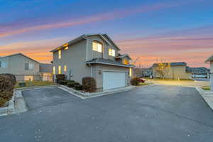 Property exterior at dusk with stucco siding, driveway, and an attached garage
