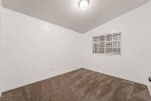 Spare room featuring vaulted ceiling and carpet