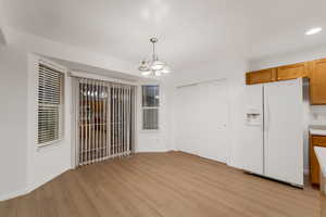 Unfurnished dining area with light wood-type flooring and a chandelier