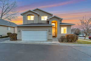 View of front of home featuring stucco siding, an attached garage, asphalt driveway, and roof with shingles