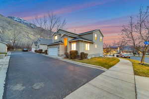 Property exterior at dusk featuring driveway, a garage, and a lawn