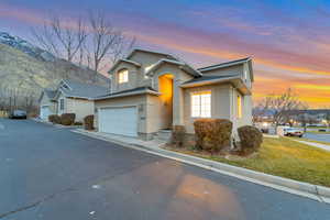 Traditional home featuring stucco siding, driveway, an attached garage, and a front lawn