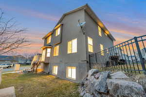 View of side of home featuring stairs, a lawn, and stucco siding