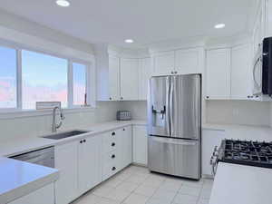 Kitchen featuring appliances with stainless steel finishes, white cabinetry, light stone countertops, light tile patterned floors, and recessed lighting