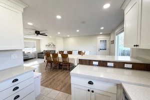 Kitchen featuring white cabinetry, light stone counters, recessed lighting, light tile patterned floors, and a peninsula