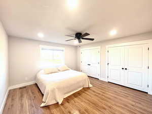 Bedroom with multiple closets, light wood-style floors, ceiling fan, and recessed lighting