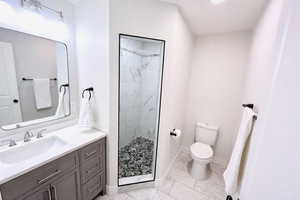 Full bathroom with light marble finish flooring, a shower stall, and vanity