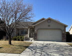 Ranch-style home featuring a garage, stucco siding, concrete driveway, and brick siding