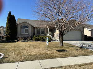 Ranch-style house featuring stucco siding, a front yard, driveway, and a garage