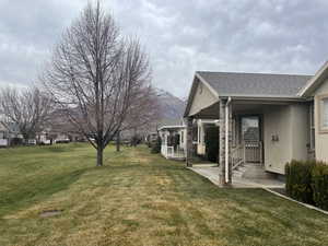 View of grassy yard featuring covered porch and a mountain view
