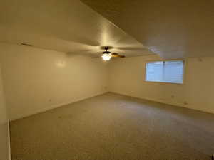 Carpeted spare room with a textured ceiling and a ceiling fan