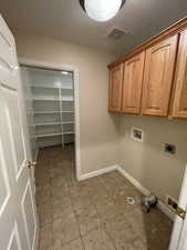 Laundry area featuring washer hookup, cabinet space, hookup for an electric dryer, and light tile patterned floors