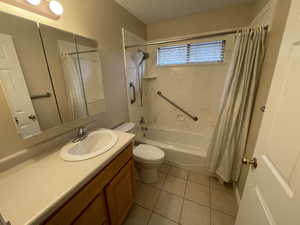 Full bath featuring vanity, light tile patterned flooring, shower / bath combo, and a textured ceiling